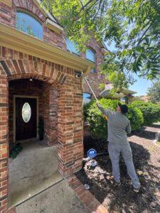 Technician performing summer Exclusion work on upper fascia to prevent rodent entry near home entrance – Celina.
