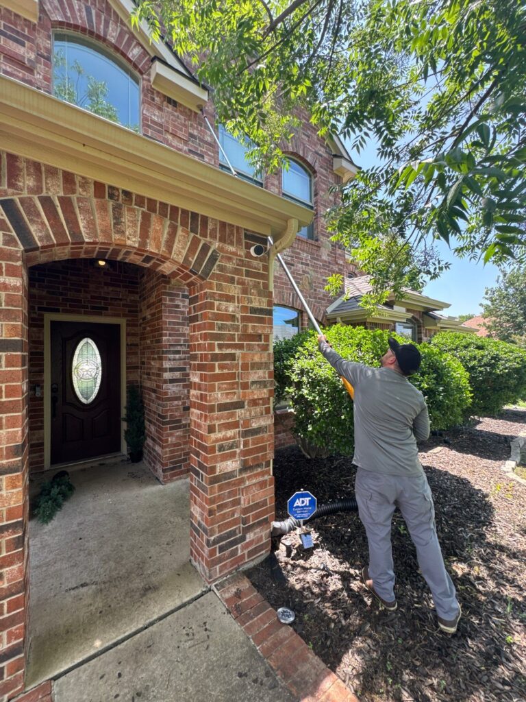 Technician performing summer Exclusion work on upper fascia to prevent rodent entry near home entrance – Celina.