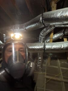 Attic exclusion work with protective gear in Frisco.