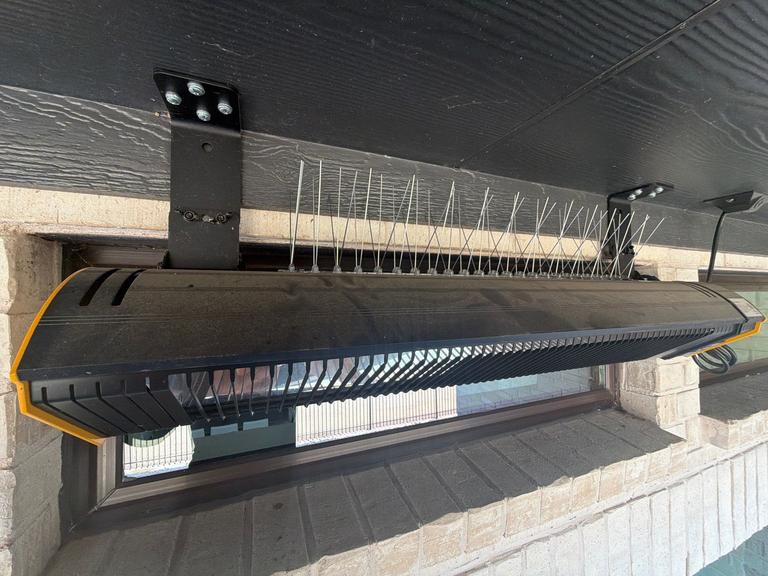 Stainless bird deterrent spikes installed along a porch cover beneath an eave at a residential home to prevent roosting birds in Little Elm, Texas.