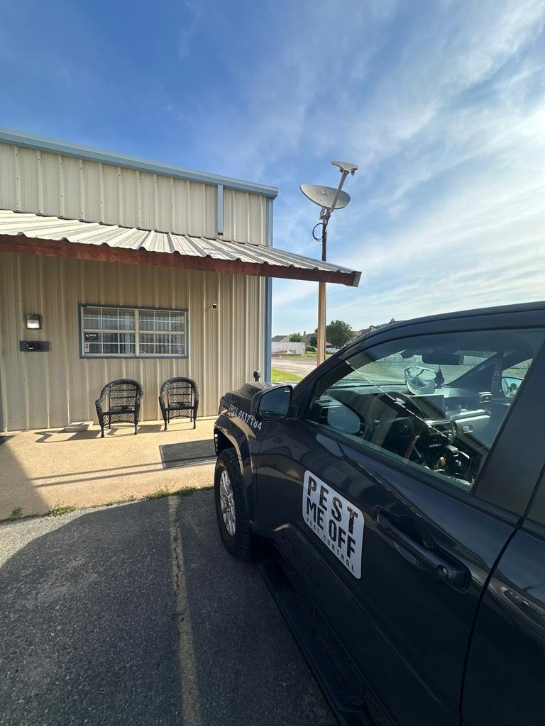 Pest control vehicle parked beside a home's metal exterior during an exterior insect perimeter inspection at the front porch in Little Elm, Texas.