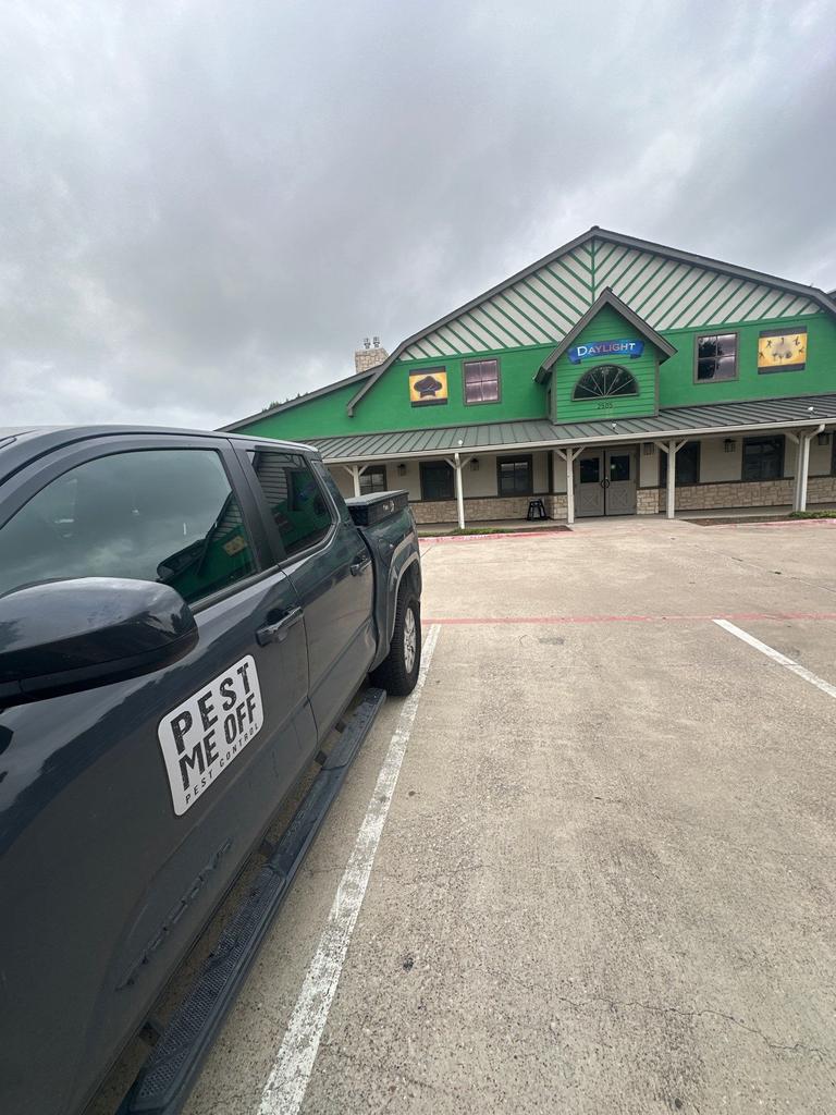 Pest Me Off truck parked outside a commercial building during routine exterior pest control inspection and preventive service in Grapevine, Texas.
