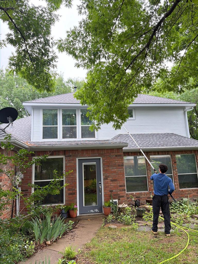 Technician uses an extension wand to treat the exterior soffit and eaves for wasp prevention at a home in Montgomery Farm, Allen, Texas.