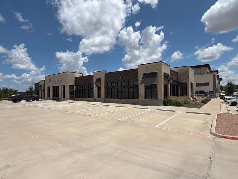 Commercial office exterior and parking lot during an ant perimeter prevention service on a sunny day in Fairview, Texas.