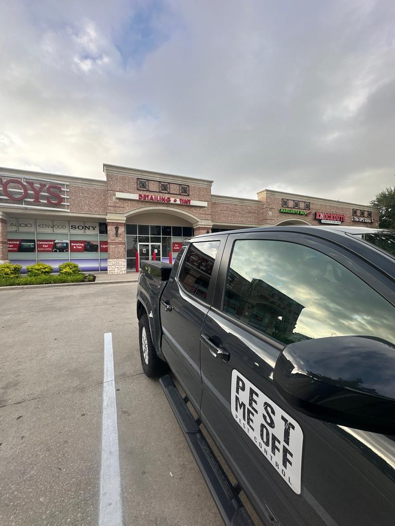 Pest Me Off service truck parked outside a shopping center during a commercial pest control visit in McKinney, Texas, before exterior inspection.